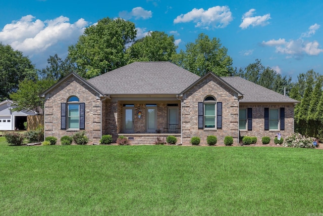 view of front of property featuring a front lawn, brick siding, roof with shingles, and covered porch