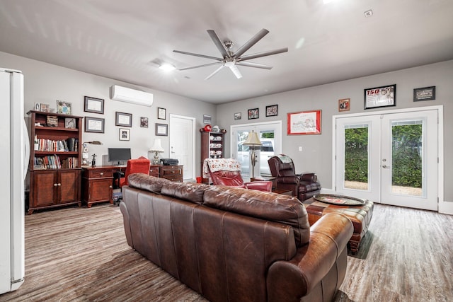 living area featuring ceiling fan, an AC wall unit, french doors, and wood finished floors