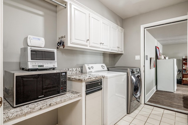 clothes washing area featuring separate washer and dryer, light tile patterned floors, a toaster, baseboards, and laundry area