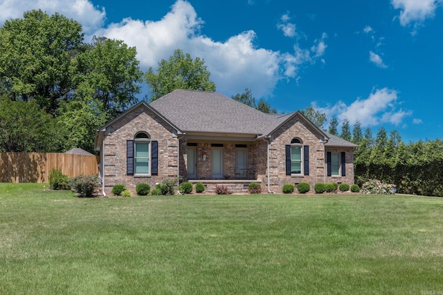 view of front of house featuring brick siding, fence, and a front yard