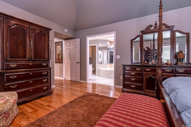 bedroom featuring ensuite bath, vaulted ceiling, light wood-style floors, and baseboards