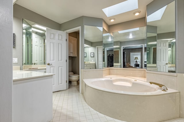 bathroom with tile patterned flooring, toilet, vanity, a skylight, and a garden tub