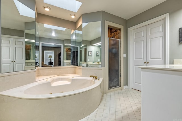 full bath with tile patterned floors, a stall shower, a skylight, a whirlpool tub, and vanity