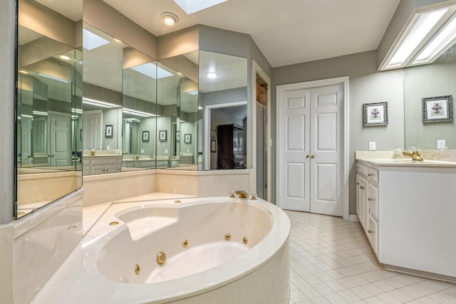 bathroom featuring tile patterned flooring, vanity, a skylight, and a tub with jets