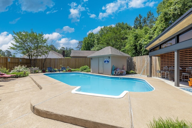 view of swimming pool with a fenced in pool, a fenced backyard, a patio area, an outdoor structure, and a storage unit