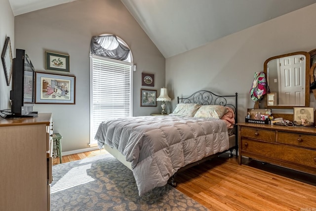 bedroom featuring vaulted ceiling, light wood-style floors, and baseboards