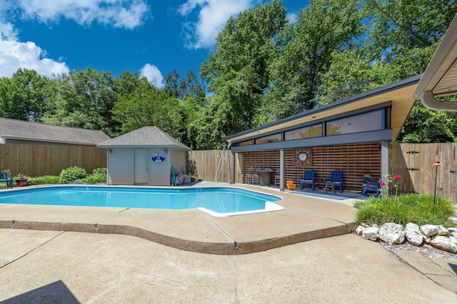 view of swimming pool featuring a storage shed, a fenced in pool, a fenced backyard, an outdoor structure, and a patio