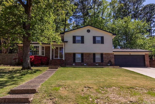 split level home featuring fence, driveway, brick siding, a front yard, and a garage