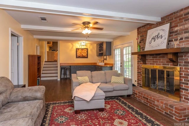 living room featuring hardwood / wood-style floors, visible vents, a ceiling fan, beamed ceiling, and stairs