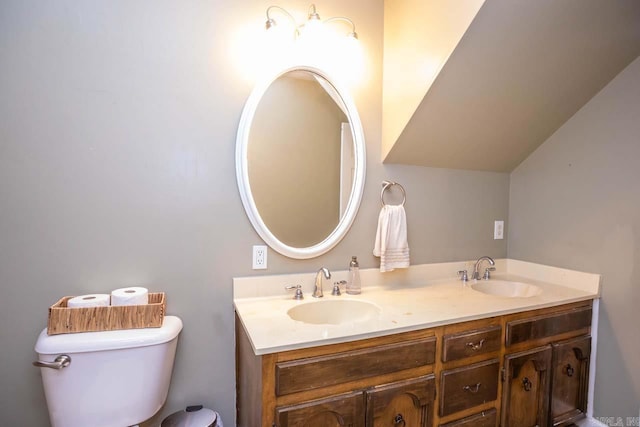 bathroom with double vanity, toilet, and a sink