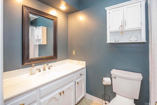 full bathroom featuring baseboards, vanity, and toilet