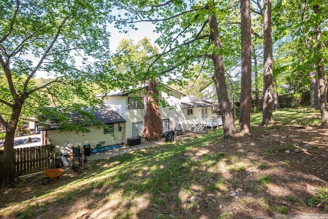 view of yard with central AC, fence, and a deck