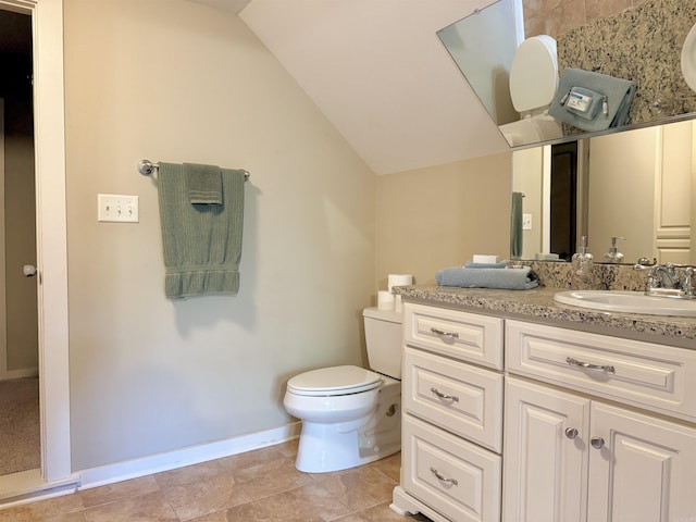 bathroom with vaulted ceiling, baseboards, vanity, and toilet
