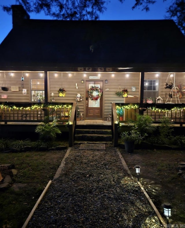 exterior entry at night with a chimney and a deck
