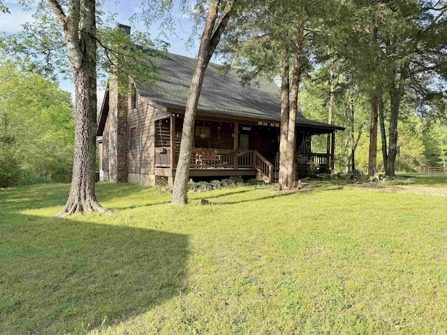 exterior space with a lawn, a shingled roof, and a chimney