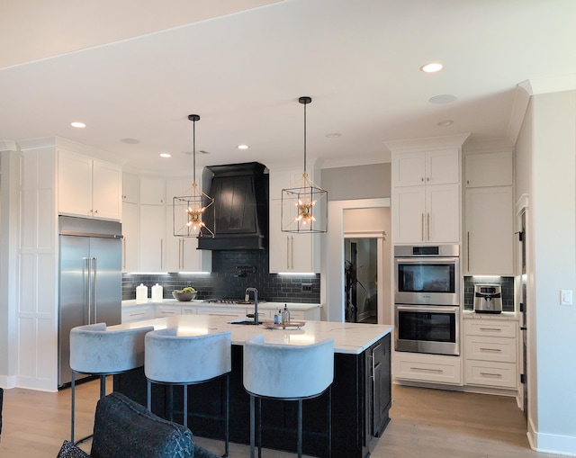 157 Manitou Dr, Maumelle, AR 72113 - kitchen featuring premium range hood, tasteful backsplash, light wood finished floors, and stainless steel appliances