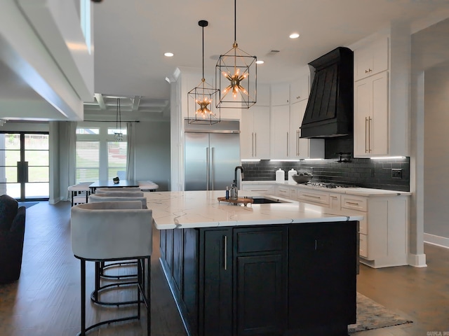 157 Manitou Dr, Maumelle, AR 72113 - kitchen with custom exhaust hood, a sink, decorative backsplash, a center island with sink, and stainless steel built in fridge