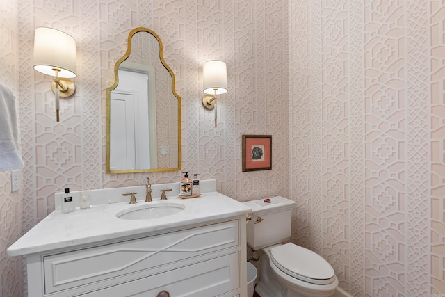 bathroom featuring wallpapered walls, vanity, and toilet