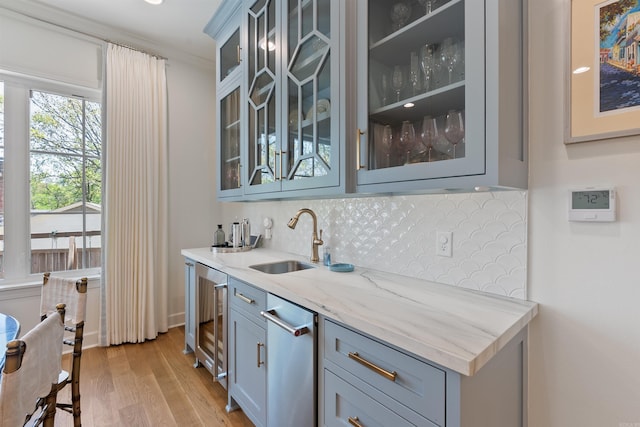 bar featuring wine cooler, a sink, light wood-style floors, backsplash, and indoor wet bar