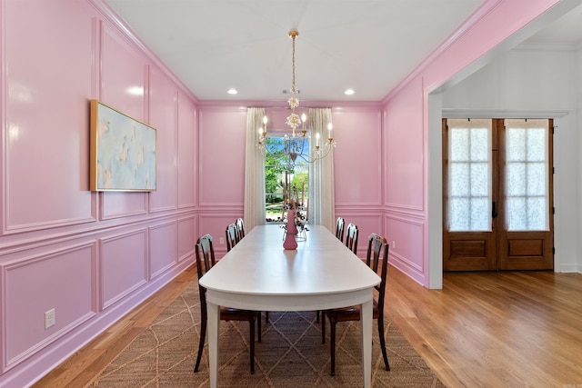 dining area with recessed lighting, light wood finished floors, a decorative wall, crown molding, and a chandelier