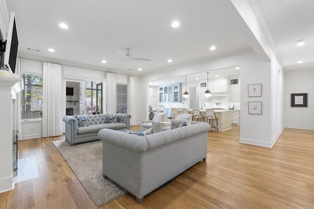 living room with recessed lighting, ornamental molding, a fireplace, light wood-style flooring, and ceiling fan