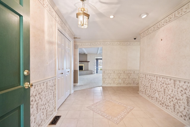 118 Grandview Dr, Hot Springs, AR 71913 - foyer with visible vents, wallpapered walls, a brick fireplace, crown molding, and light tile patterned floors