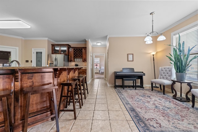 109 Sandstone Cv, Sherwood, AR 72120 - interior space featuring crown molding, hanging light fixtures, light tile patterned flooring, a breakfast bar area, and stainless steel fridge with ice dispenser