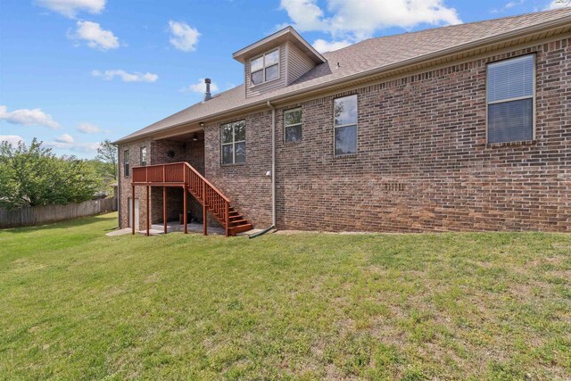 109 Sandstone Cv, Sherwood, AR 72120 - rear view of house featuring fence, brick siding, a wooden deck, a lawn, and stairs