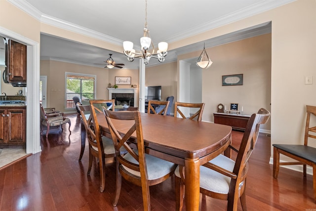 109 Sandstone Cv, Sherwood, AR 72120 - dining space with a fireplace, crown molding, dark wood-style floors, and ceiling fan with notable chandelier