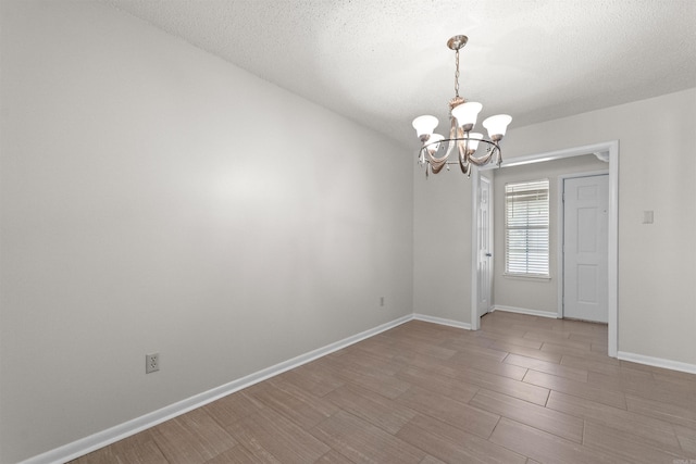 8302 Merriwood Ct, Sherwood, AR 72120 - unfurnished room featuring light wood-style flooring, a textured ceiling, baseboards, and an inviting chandelier