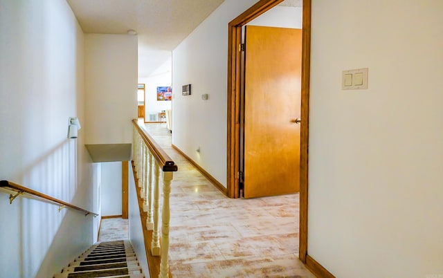 hall featuring baseboards and an upstairs landing