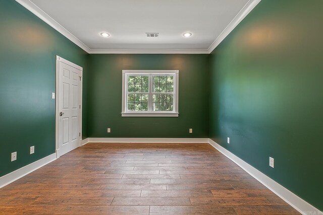 spare room with baseboards, visible vents, dark wood finished floors, and crown molding