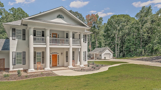 greek revival inspired property featuring a front lawn, a balcony, an outbuilding, covered porch, and a detached garage