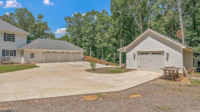 view of side of property featuring driveway, fence, and a detached garage
