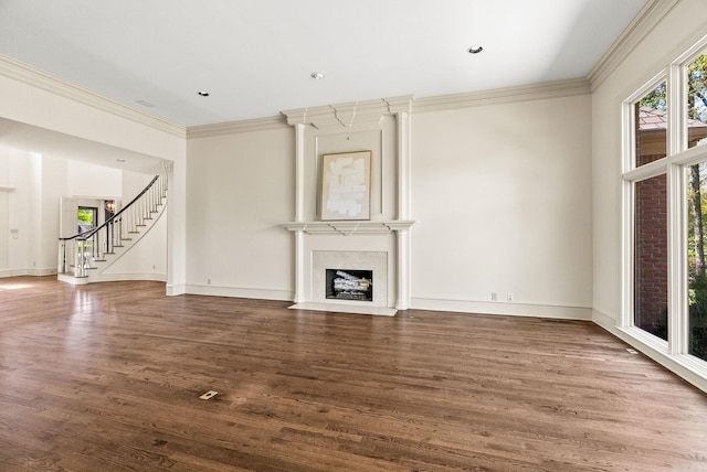 unfurnished living room with wood finished floors, ornamental molding, baseboards, a fireplace, and stairs
