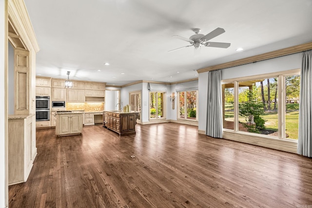 unfurnished living room with a ceiling fan, crown molding, a sink, and dark wood-type flooring