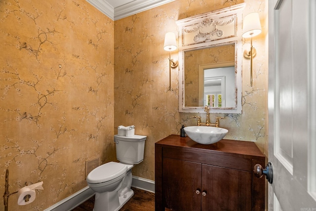 half bath featuring toilet, baseboards, wood finished floors, crown molding, and vanity