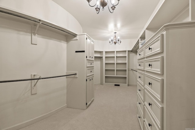 walk in closet with a chandelier and light carpet