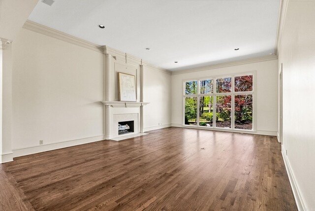 unfurnished living room featuring baseboards, wood finished floors, a large fireplace, and ornamental molding