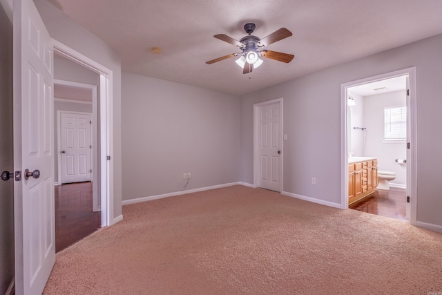 unfurnished bedroom featuring ensuite bath, carpet flooring, baseboards, and a ceiling fan