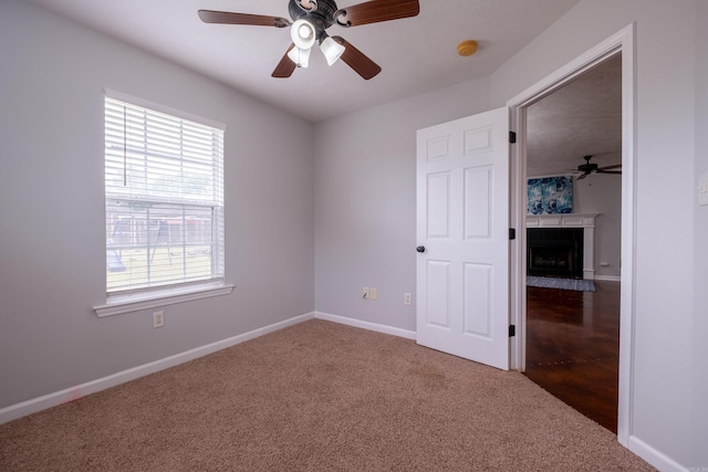 unfurnished bedroom with a fireplace with flush hearth, carpet floors, baseboards, and multiple windows