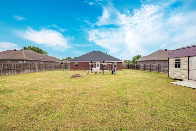 view of yard featuring a fenced backyard, an outdoor fire pit, and an outdoor structure