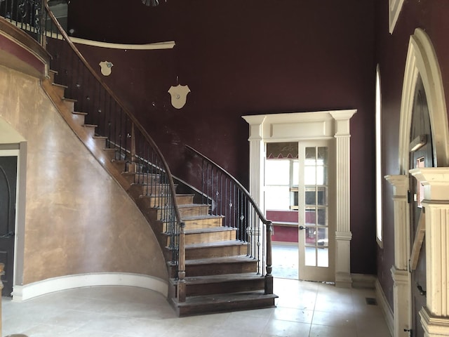 staircase featuring a high ceiling, baseboards, and french doors