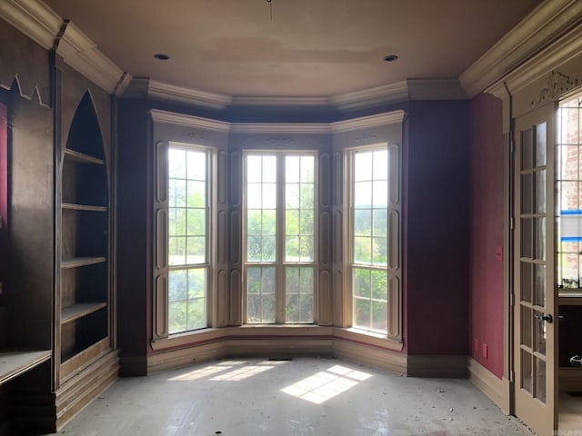 spare room with arched walkways, a wealth of natural light, crown molding, and baseboards