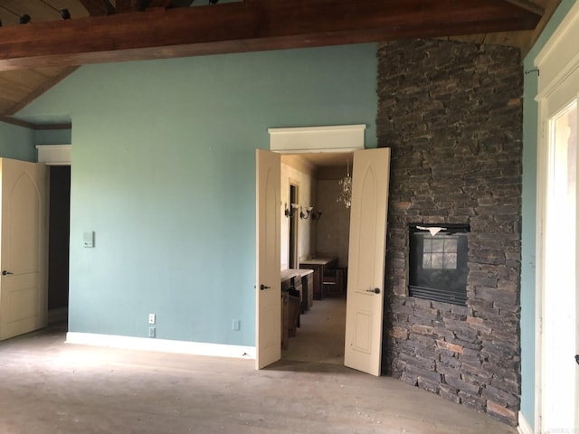 interior space featuring baseboards, vaulted ceiling with beams, and a fireplace