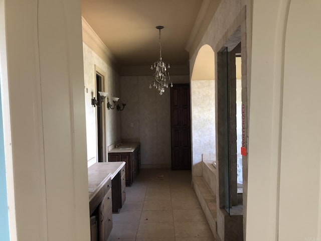 mudroom featuring a notable chandelier, ornamental molding, and light tile patterned floors