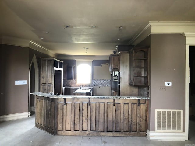 kitchen featuring visible vents, ornamental molding, baseboards, decorative backsplash, and a peninsula