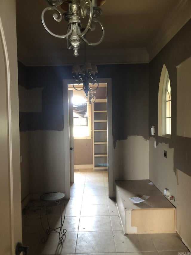 unfurnished dining area featuring plenty of natural light, arched walkways, a chandelier, and light tile patterned floors