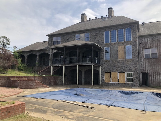 exterior space featuring stairway, a patio area, a chimney, and a covered pool