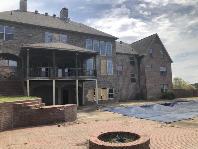 back of house featuring a fenced in pool, a fire pit, a chimney, and a patio
